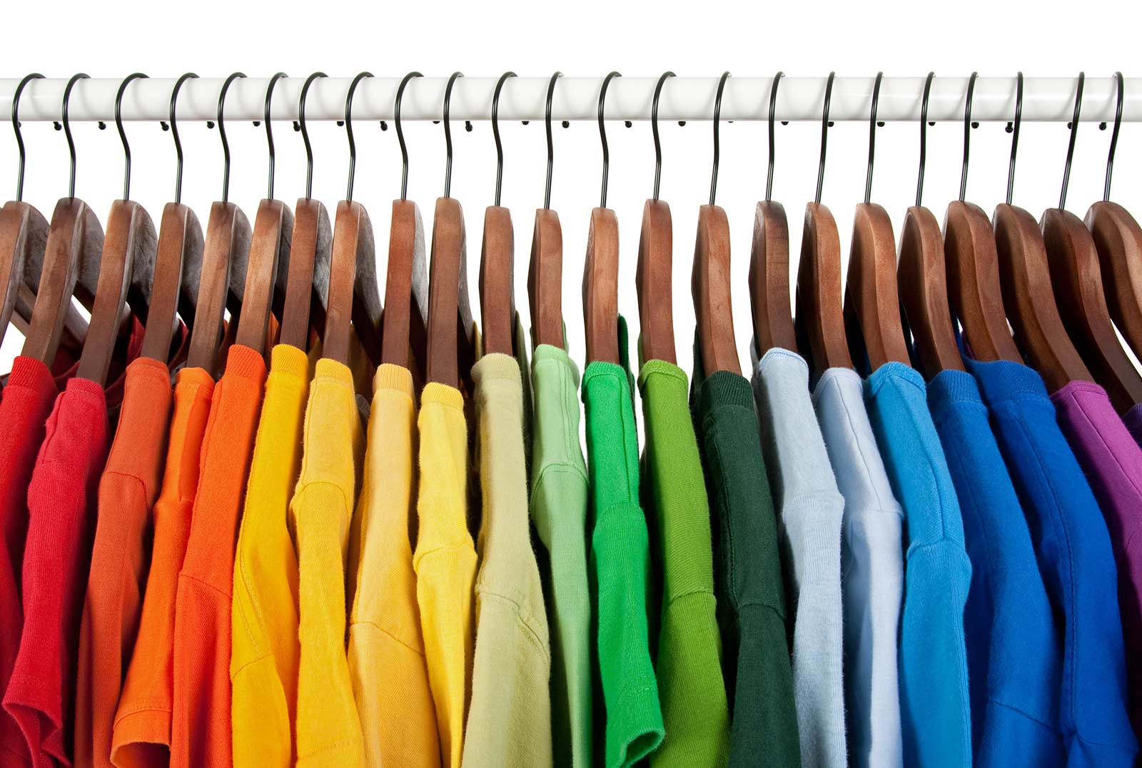 Rainbow colored clothes on a rack.