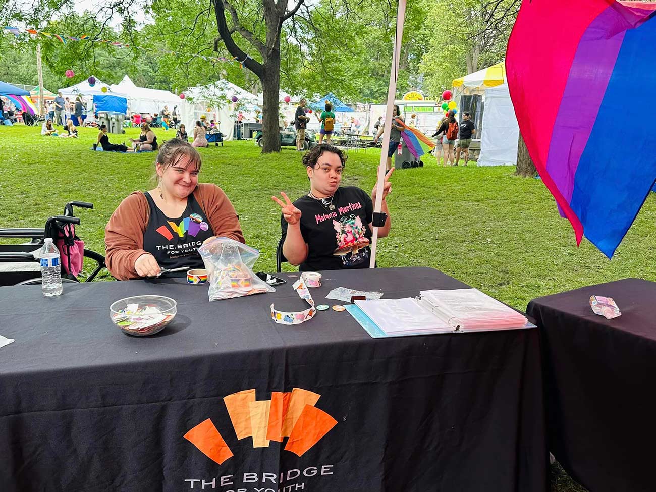 Two young girls volunteering at the TC Pride festival Bridge for Youth booth.
