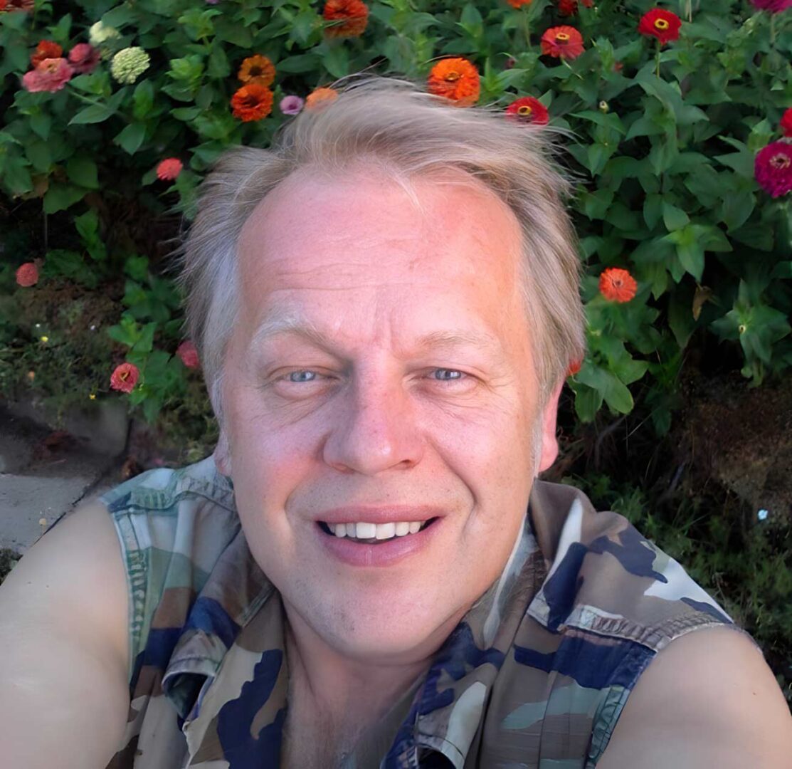 Selfie of Richard Simon with some flowers in the background.