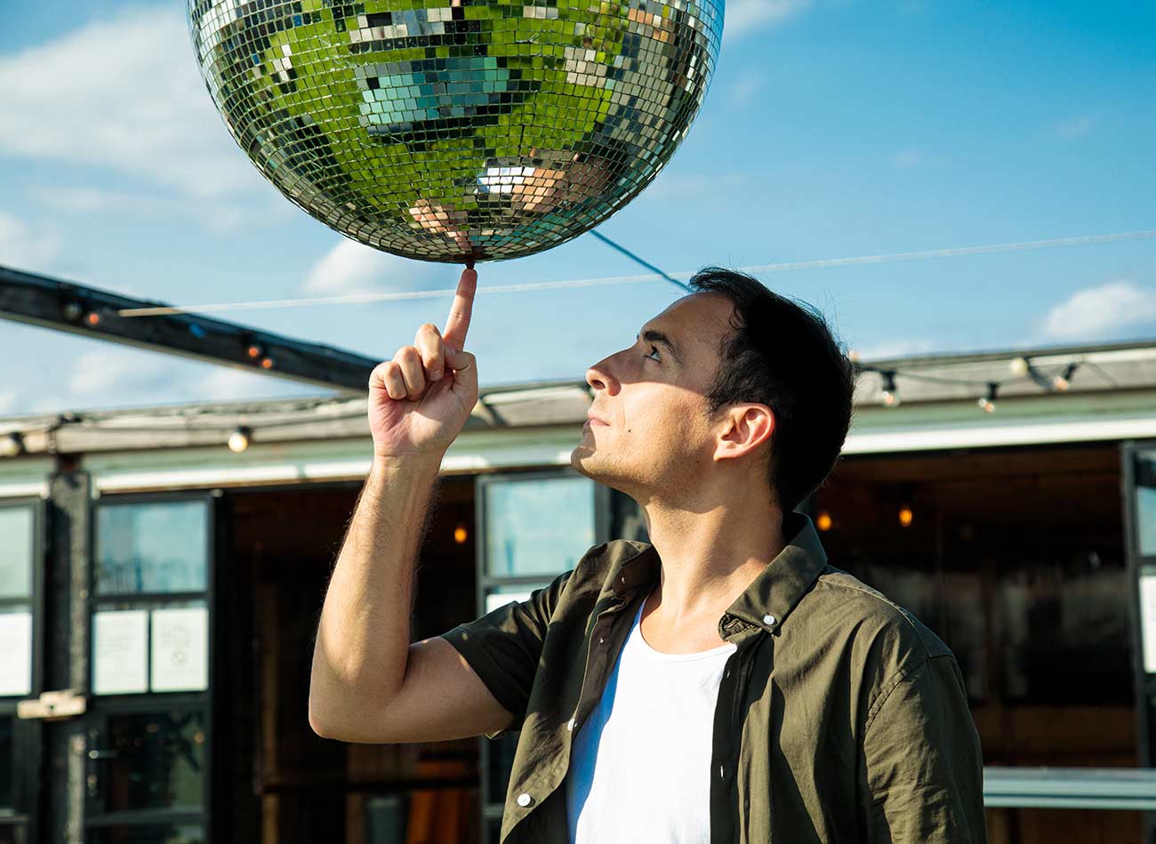 Musical artist Matt Fishel spinning a disco ball on his finger.