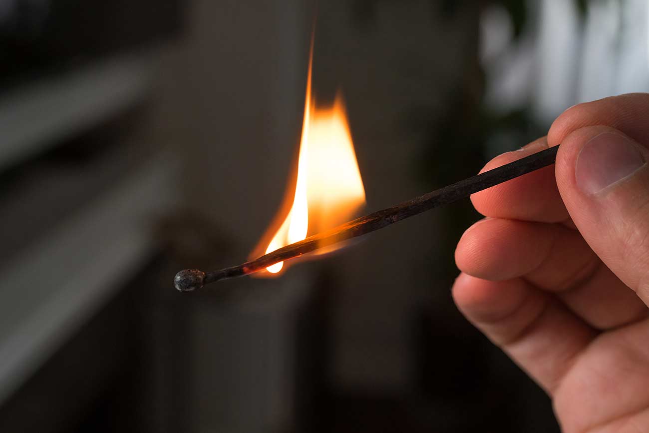 Save Download Preview Hand with burning match. A Match ignited by rubbing the match head against a match box.