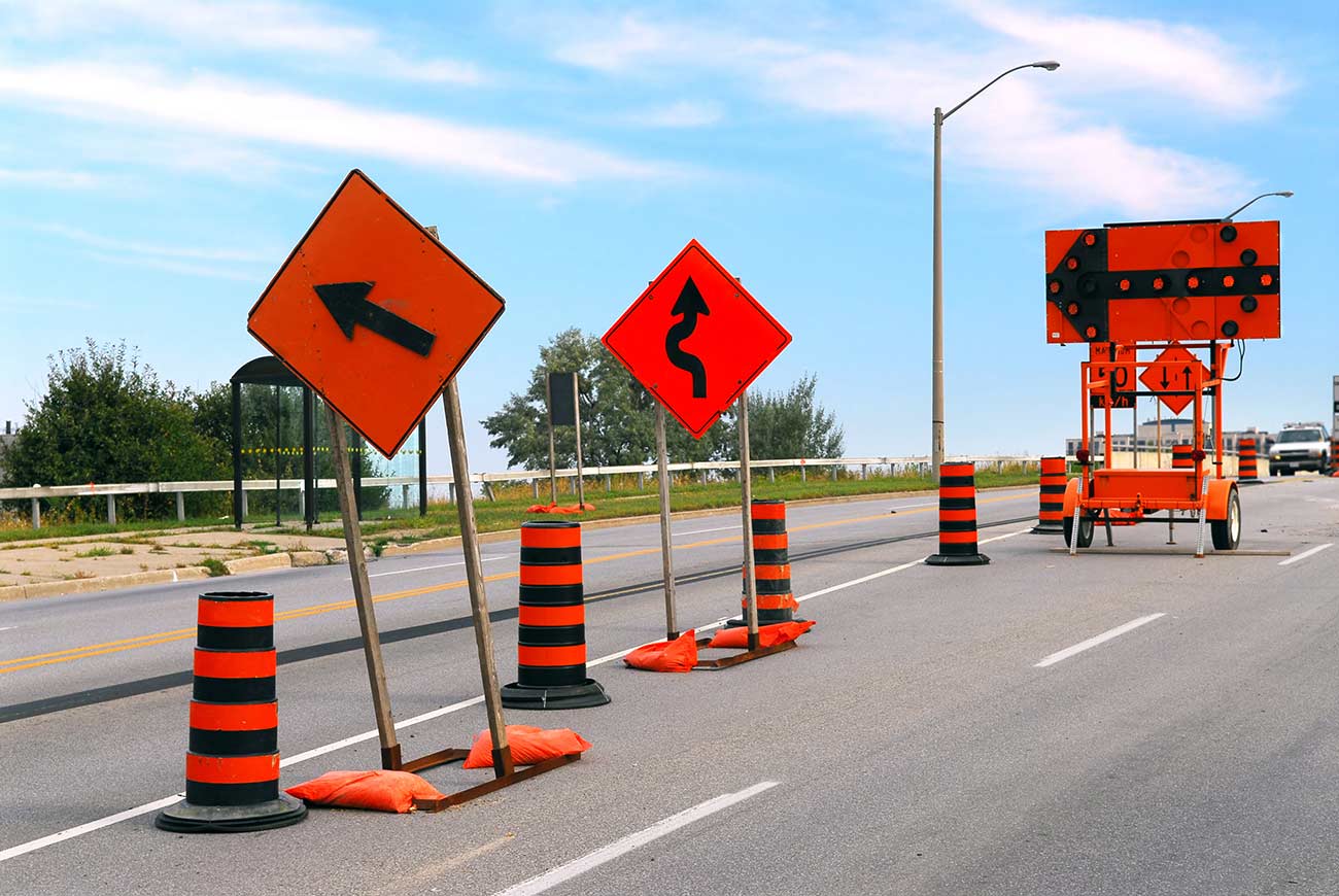 Road construction signs and cones on a city street.