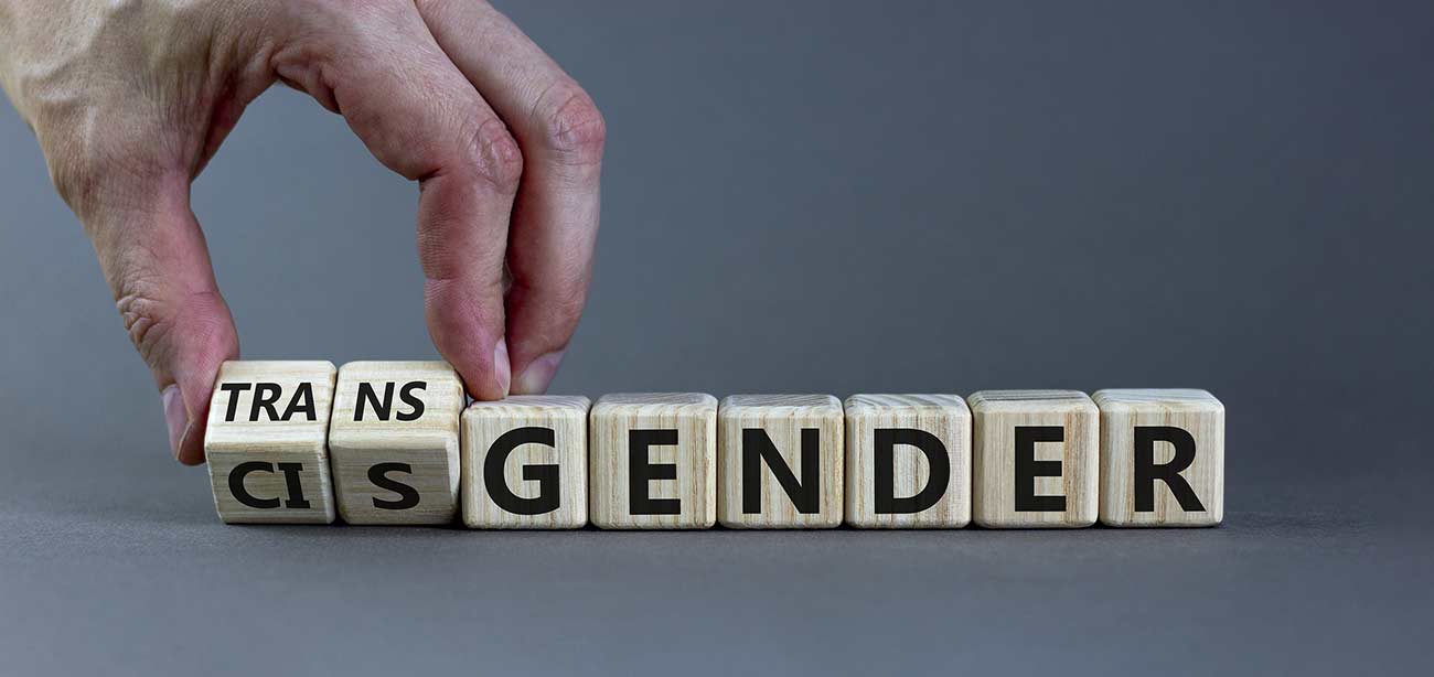 Male hand flips wooden cubes and changes word cisgender to transgender.