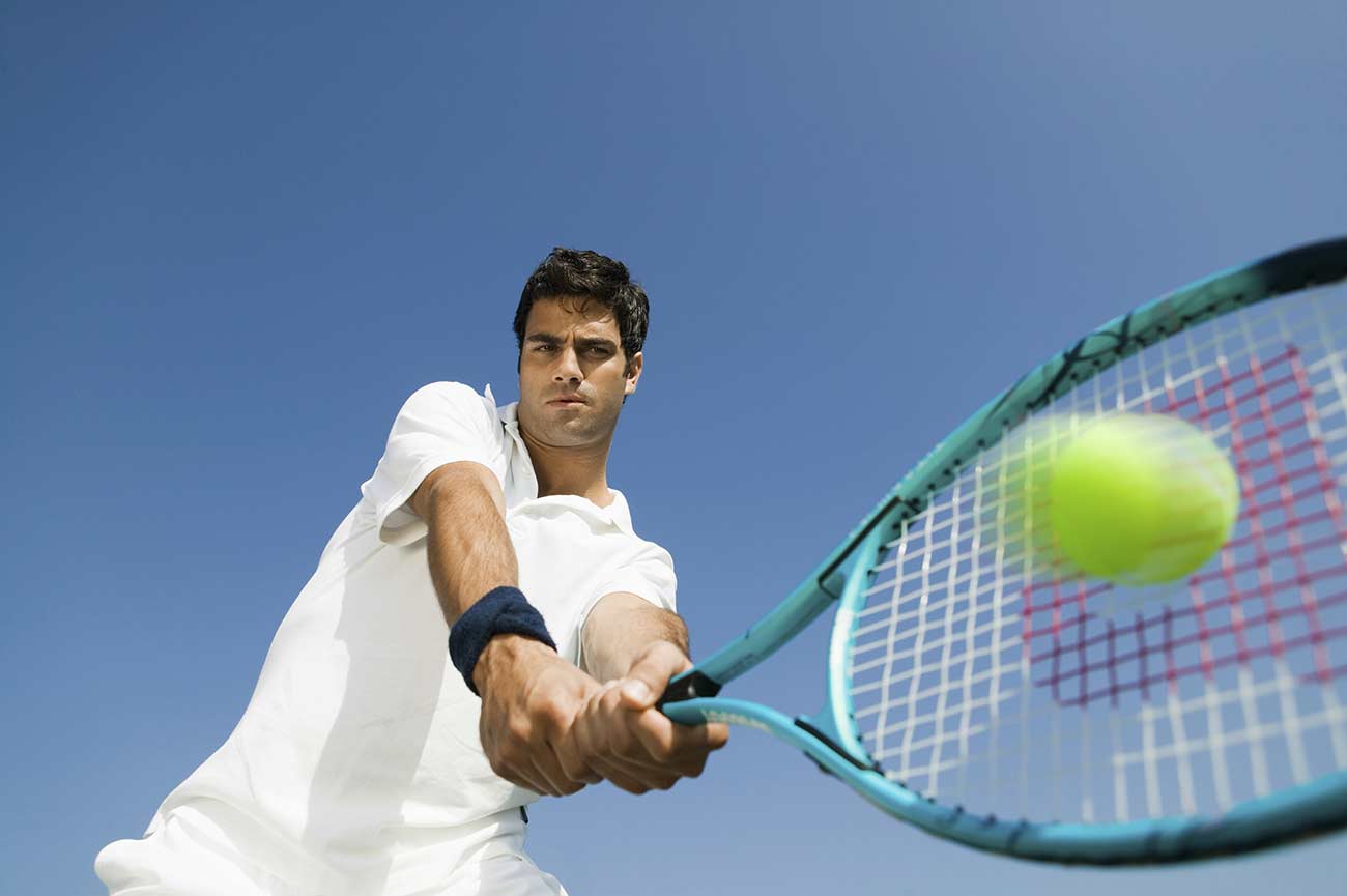 Low angle view of a young man playing tennis.