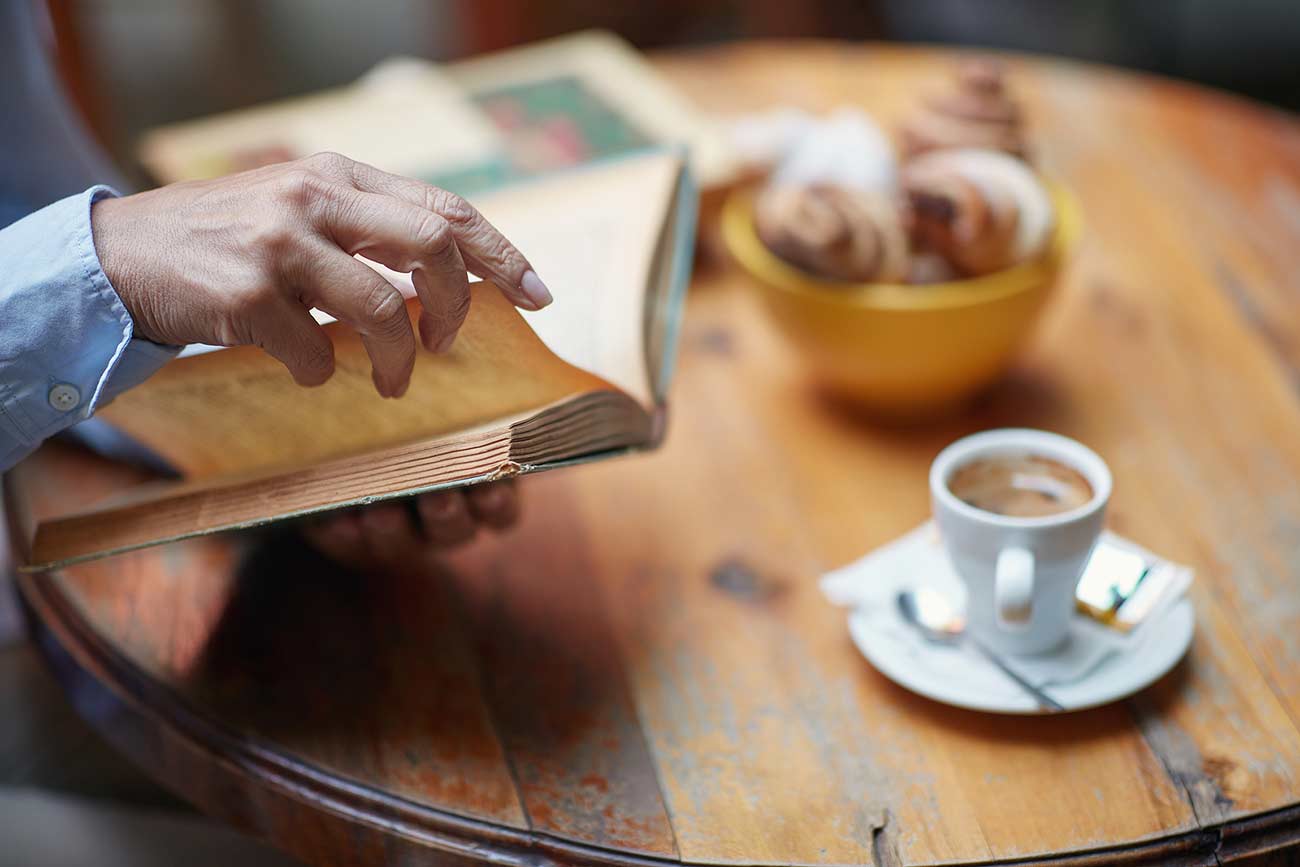 Elderly woman's hand holding a book turning page.