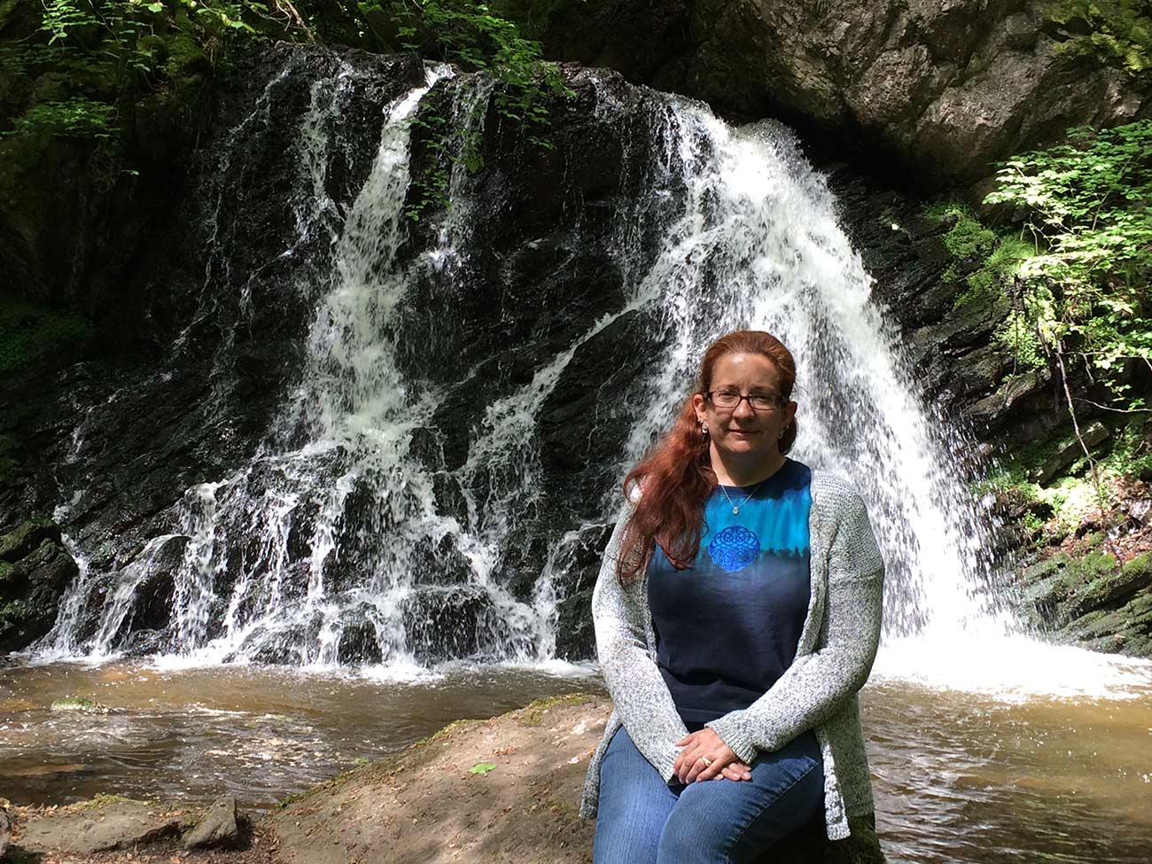 Linda Raines sitting on a rock by a waterfall at Black Isle.