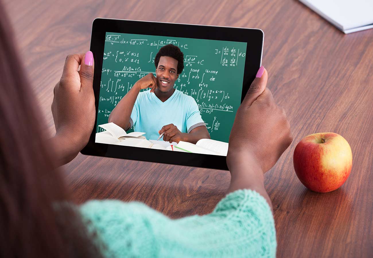 Teacher assisting student through video conferencing at classroom.